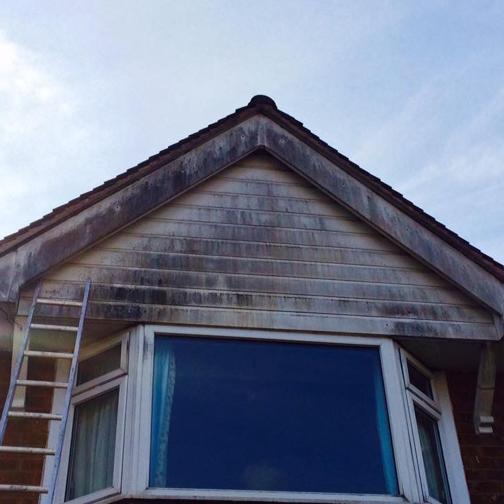 Gable end and window covered in green algae and dirt before cleaning in Nottingham